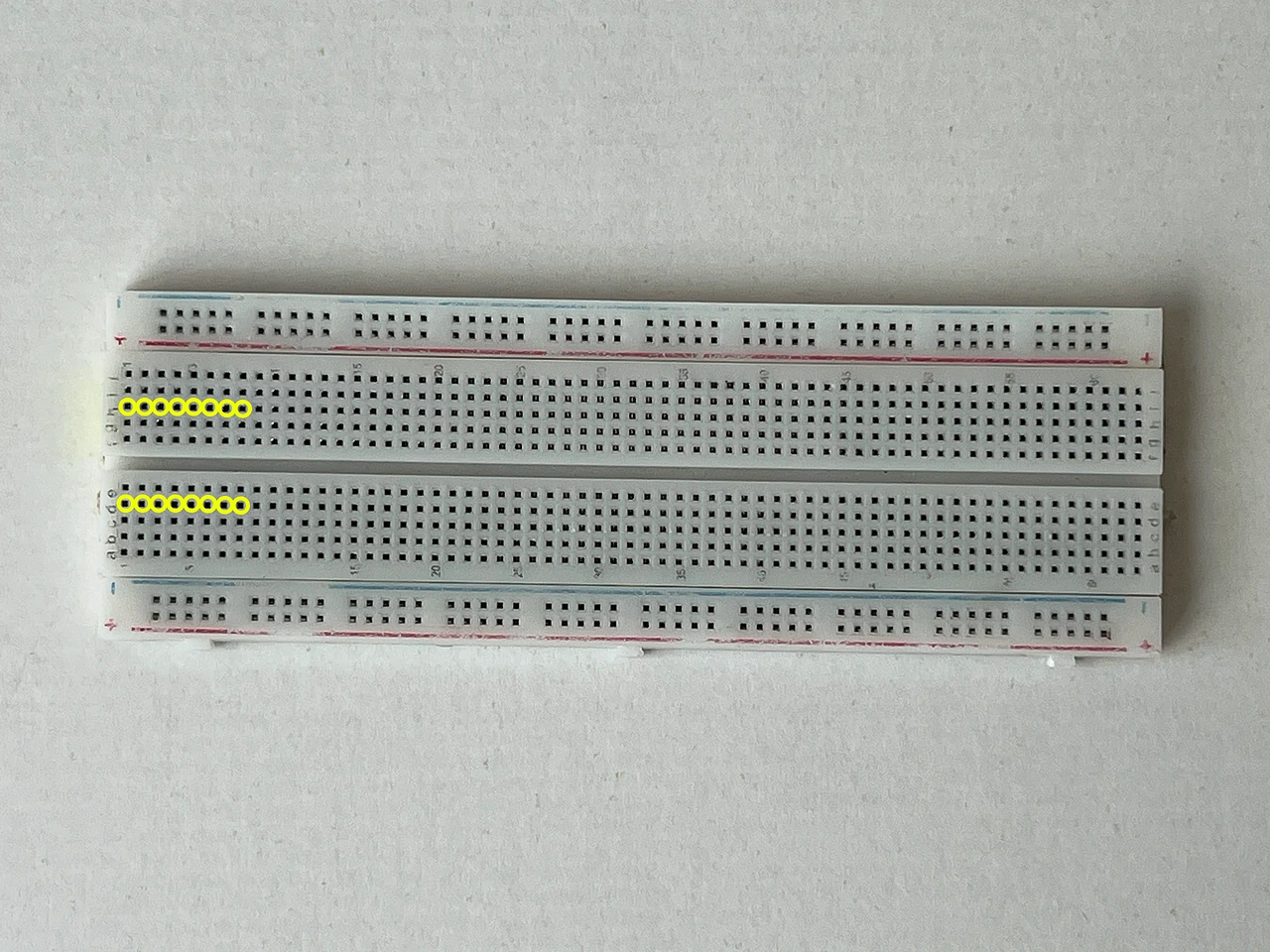 Das ganze Steckbrett von oben. Gelbe Ringe markieren die Löcher D1 bis D9 und H1 bis H9. Dorthin kommt der Chip.